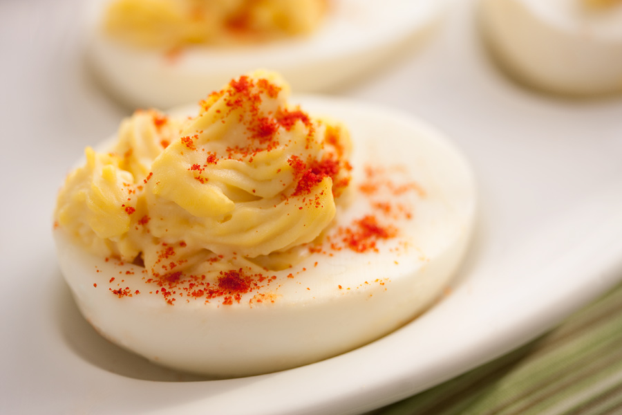 This is Brian Charles Steel close up food photograph of a deviled egg with paprika on it.  The yoke mix was placed in the white with a pastry bag.  The egg is lit from behind and takes up most of the frame.  It was shot with a macro lens and has a shallow depth of field. 